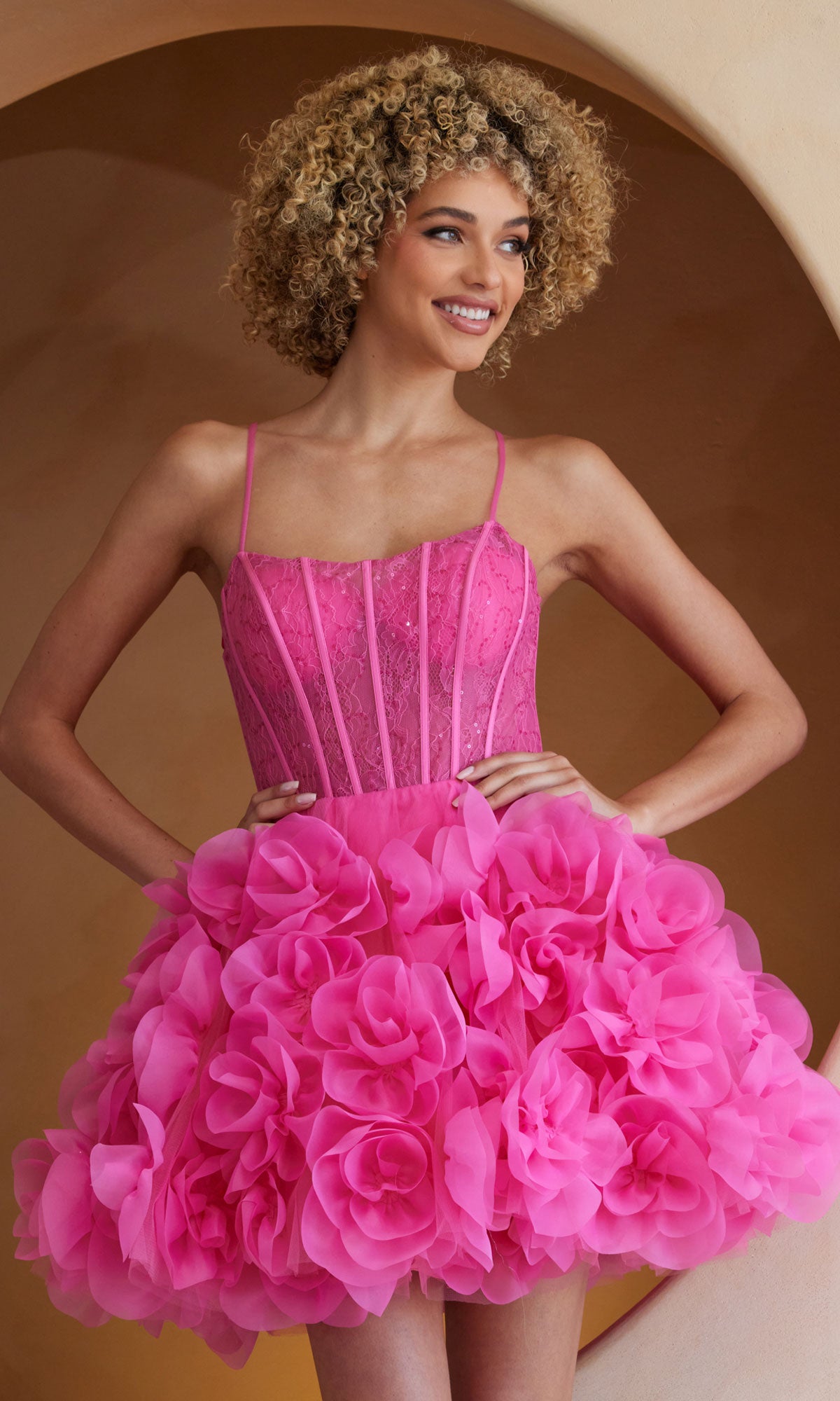 A woman models the Amelia Couture SU083S Short Pink Homecoming Dress, showcasing its corset bodice and layered floral skirt for a standout party look.